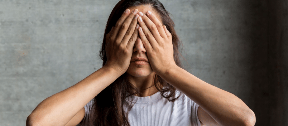 mulher tapando os olhos com as duas mãos