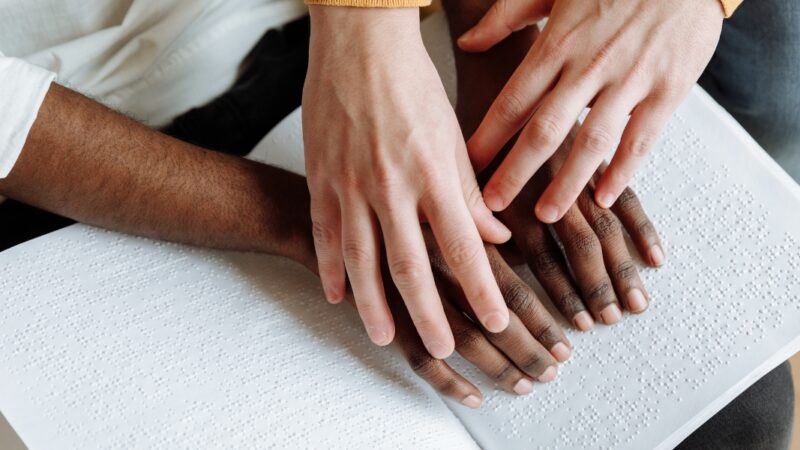 mãos de várias raças lendo braile (abril marrom)